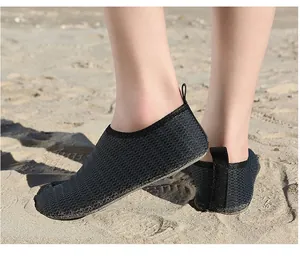 Detailed view of black mesh quick-dry water shoes worn on sand for beach and swimming