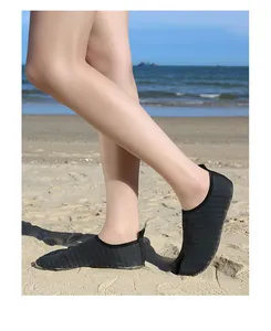 Detailed view of unisex black mesh split-toe aqua shoes worn on a sunny beach