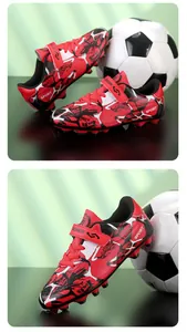 Gros plan de chaussures de foot pour enfants rouges et noires avec bandes velcro.