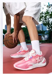 Detailed view of pink and white low-top basketball shoes on an outdoor court setting.