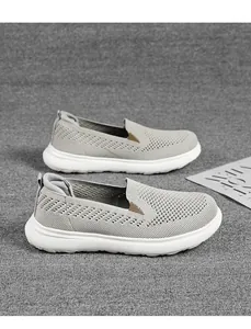 Side detail view of grey knit slip-on sneakers featuring a breathable mesh upper and white sole