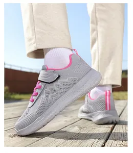 Vista dettagliata di sneakers in maglia grigia traspirante con dettagli rosa su legno.
