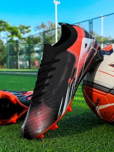 Professional red and black soccer cleats with firm ground studs on a green field