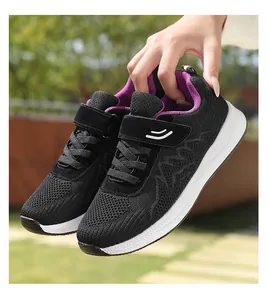 Primo piano di scarpe da ginnastica in mesh nero traspirante tenute in mano all'aperto.