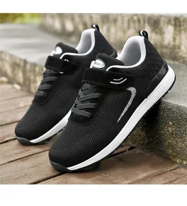 Detailed side view of black breathable fly-knit walking sneakers with velcro straps.
