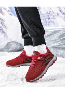 Rote gefütterte Winter-Walkingschuhe mit rutschfester Sohle auf verschneitem Boden