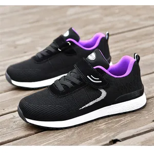Detail view of lightweight black and purple fly-woven mesh sneakers on a wooden deck