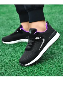 Close-up detail of breathable black and purple flyknit walking shoes on green grass