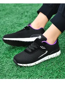 Detail showing breathable black flyknit mesh walking shoes on green grass backdrop