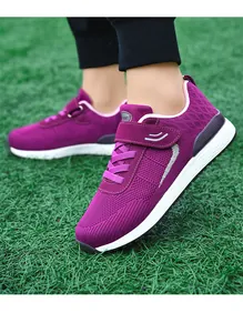 Close-up of purple fly-woven breathable walking sneakers worn on a green turf background