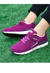 Close-up of purple breathable mesh walking shoes with Velcro strap on green grass.