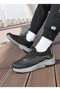 Close-up of black slip-on sneakers with grey soles and leather texture outdoors