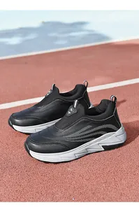 Detail of black slip-on walking shoes with leather upper on a red running track.
