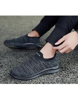 Detailed view of grey flyknit sock sneakers worn on feet in an outdoor setting