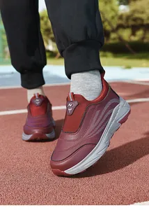 Side detail view of burgundy slip-on walking shoes for elderly on a running track