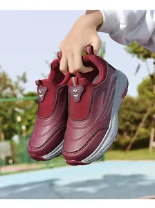 Detail view of burgundy slip-on walking shoes for elderly being held in an outdoor setting