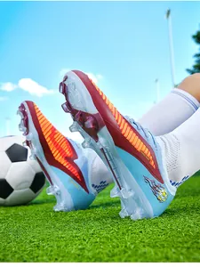 Close-up of blue knitted soccer cleats with long studs on a green grass field