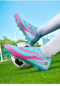 Side view of cyan and pink flyknit soccer cleats with firm ground spikes on field
