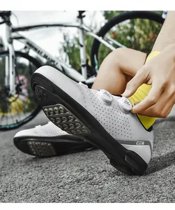Macro view of white cycling shoes featuring rotary buckle and breathable hole details.