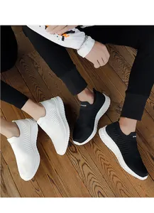 Macro view of black and white breathable flyknit sock sneakers on a wooden floor
