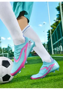Action shot of blue flyknit soccer cleats with pink accents on green grass field