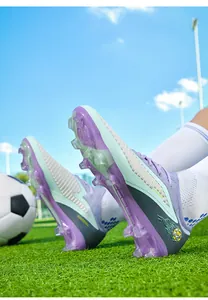 Detailed view of purple and teal soccer cleats with FG studs and knit upper on grass