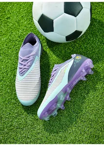 Detailed side view of purple fly-knit soccer cleats with FG studs on a grass pitch field.