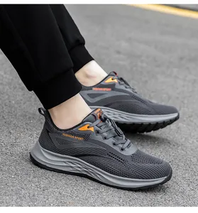 Side view of grey flyknit mesh running shoes with orange accents on asphalt