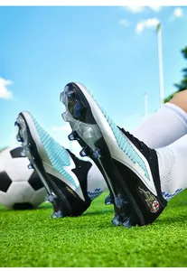 Detail view of low-top fly-knit soccer cleats with FG studs on a green grass field.