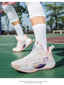 Action detail shot of breathable low-top basketball shoes in pink and white on court.
