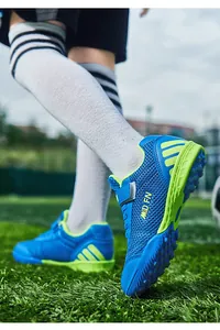 Vue détaillée des chaussures de football bleues et vert fluo pour enfants sur gazon
