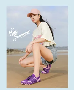 Purple five-finger water shoes shown on a beach by a female model for summer sports