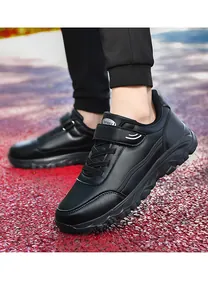 Macro view of black faux leather walking shoes for seniors on a red outdoor track surface