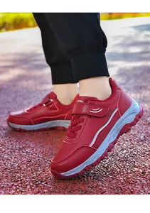 Detailed side view of red leather walking shoes with velcro straps and wavy white soles.