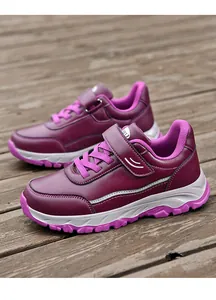 Close-up of purple leather walking shoes for elderly with Velcro straps on wooden floor