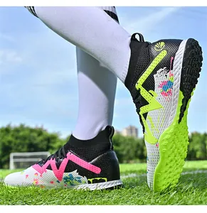 Close-up of high-top soccer shoes with vibrant paint splash design on green turf