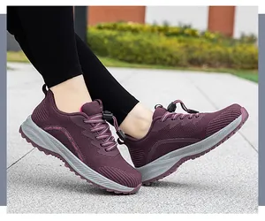 Detailed side view of breathable burgundy mesh walking shoes worn outdoors on a paved path