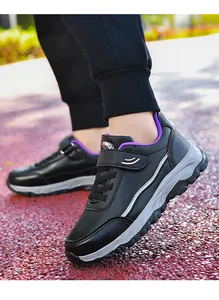 Detailed view of black leather walking shoes with purple lining and durable grey soles.