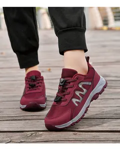 Detailed view of maroon mesh walking shoes with quick-lace system on wooden deck