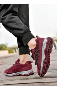 Detailed side and sole view of burgundy breathable walking shoes on a wooden path outdoors