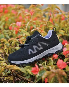 Detailed side view of breathable black mesh outdoor walking shoes nestled in red flowers.
