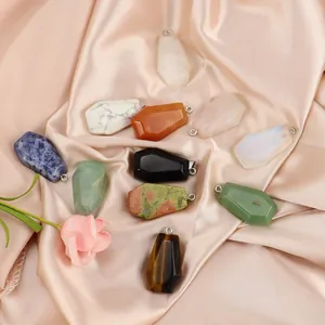 Collection of coffin-shaped natural crystal stone pendants displayed on elegant pink silk