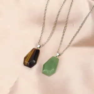 Macro view of natural tiger eye and green stone coffin pendant necklaces on silk.