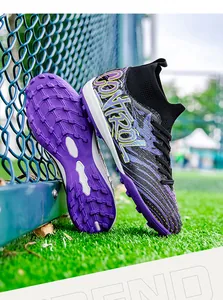 Close-up detail of mid-top fly-knit soccer shoes with purple TF outsoles on turf grass