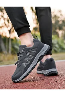 Close-up view of dark grey mesh walking shoes worn on an outdoor running track surface