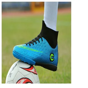Detailed macro view of high-top blue soccer turf shoes on a grass field stepping on a ball