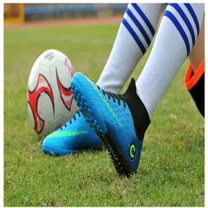 Close-up of blue high-top soccer shoes with TF turf outsole on a grass field