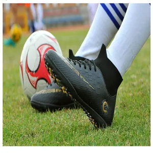 Close-up of high-top black soccer cleats with turf studs on a green grass field detail