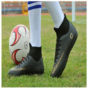 Action shot of high-top black soccer shoes with gold details on a green grass field