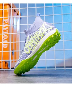 Detailed macro view of youth high-top purple knit soccer shoes with green turf studs